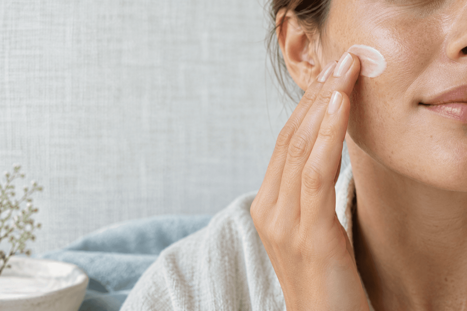 An anonymous person applying moisturizer to naturally textured skin