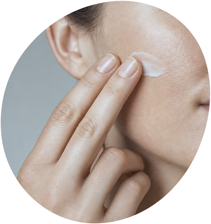 Fingers applying moisturizer to a cheek.